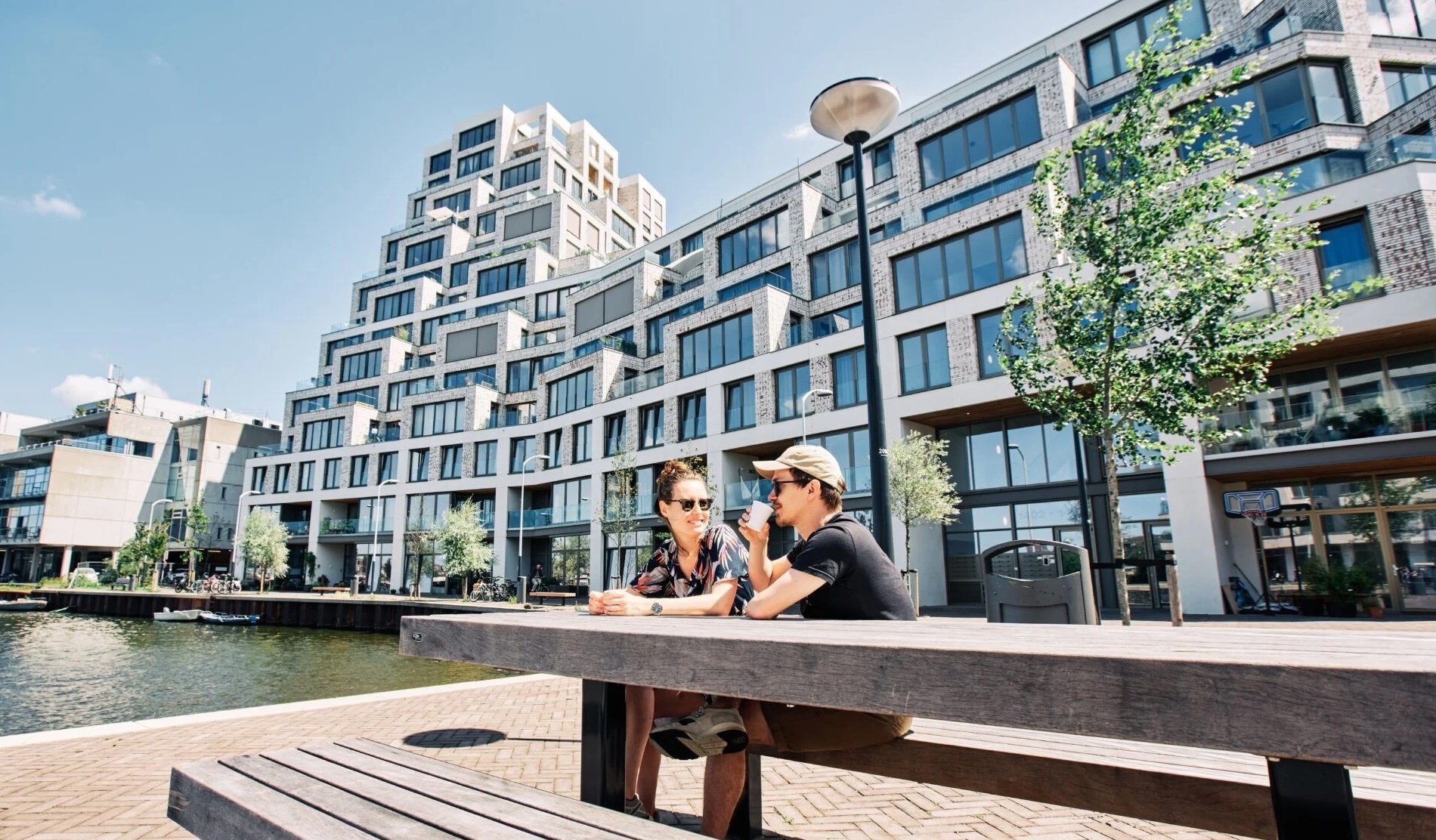 Cruquiuseiland-nieuwbouw-appartementen-stadswoningen-Amsterdam-mensen-op-bankje-aan-het-water