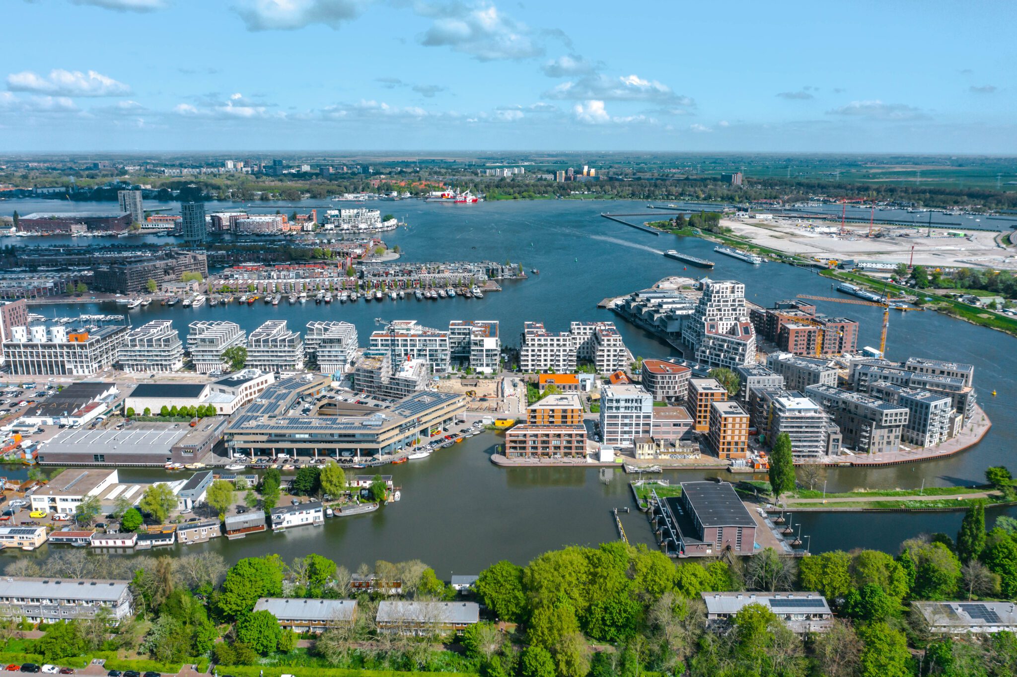Luchtfoto van Cruquius in Amsterdam-Oost, met zicht op de Entrepothaven, het IJ en de karakteristieke moderne bebouwing van het schiereiland, omringd door water en groene zones.