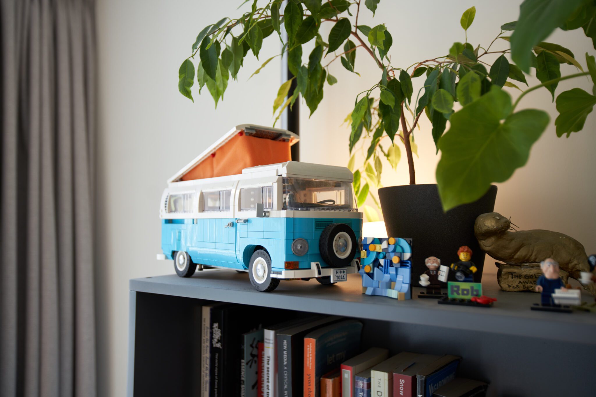 Nabijbeeld van de bovenkant van Robs boekenkast, met een blauw LEGO-camperbusje, een plant en diverse kleine figuren en persoonlijke objecten met karakter.