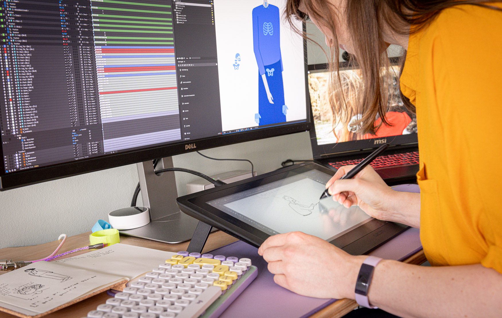 Close-up van een illustrator die tekent op een tekentablet met twee beeldschermen vol animatieprojecten.